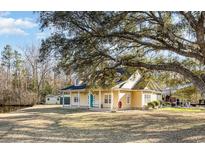 Charming yellow home with a bright teal door and a welcoming front porch swing under a large shaded tree at 2724 A C Ln, Conway, SC 29526