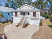 Charming raised beach house with a metal roof and double garage, surrounded by trees at 31 Tidelands Trail, Pawleys Island, SC 29585