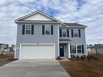 Two-story home showcasing light blue siding, dark shutters, and a two-car garage, complemented by a well-manicured front yard at 445 Acosta Circle, Conway, SC 29527