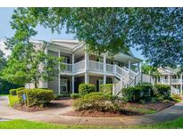 Charming condo with white stair railings, lush landscaping and a large tree providing ample shade at 581 Blue Stem Dr. # 76C, Pawleys Island, SC 29585