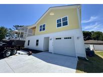 Two-story yellow and white home with a concrete driveway and two-car garage, perfect for coastal living at 713 9Th Ave. S, North Myrtle Beach, SC 29582