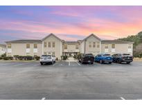 Exterior of condominium with ample parking, landscaped grounds, and sunset hues at 8538 Hopkins Circle # E, Surfside Beach, SC 29575