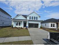 Charming two-story home with light blue siding, a modern black door, and a spacious two-car garage at 1609 Seachase Way, North Myrtle Beach, SC 29582