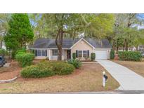 Charming single story home featuring mature trees, a well manicured front yard, and an attached garage at 177 Reef Run Rd., Pawleys Island, SC 29585