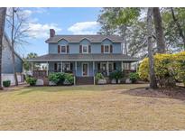 Charming two-story home featuring a welcoming wrap-around porch, blue siding, and a well-manicured front lawn at 317 14Th Ave. N, Surfside Beach, SC 29575