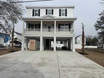 Beautiful two-story home featuring a spacious porch, elevated construction, and a large concrete driveway at 318 Vista Dr., Murrells Inlet, SC 29576