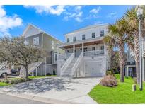 Beautiful beach home with a two-car garage, green lawn, palm trees, and a private front porch at 89 Enclave Pl., Pawleys Island, SC 29585