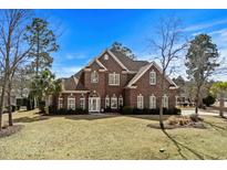 Beautiful brick home with manicured lawn and mature trees under a bright blue sky at 900 Berwick Ln., Myrtle Beach, SC 29579