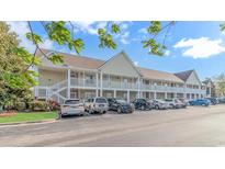 A tan two-story condo building with white railing and staircase is surrounded by parked cars at 135 Butkus Dr. # 5, Myrtle Beach, SC 29588