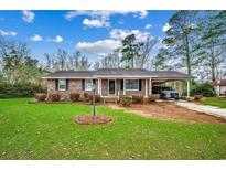 Charming brick ranch home with a well-manicured lawn, attached carport, and mature trees at 4810 Circle Dr., Loris, SC 29569