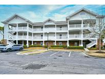 Three-story condo with white railings, brick accents, and ample parking in front at 5750 Oyster Catcher Dr. # 1034, North Myrtle Beach, SC 29582