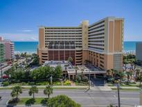 Stunning exterior shot of an oceanfront high-rise condo building with lush landscaping and direct beach access at 6900 N Ocean Blvd. # 1235, Myrtle Beach, SC 29572
