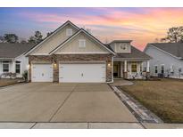 Charming home with stone accents, manicured lawn, and a spacious two-car garage beneath a colorful sunset at 808 Kingfisher Dr., Myrtle Beach, SC 29577