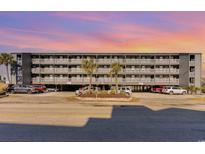 Four-story condo building featuring gray siding, balconies with white railings and a ground level parking area, and a colorful sunset at 123 Dogwood Dr. N # 205-A, Murrells Inlet, SC 29576