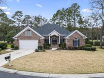 Charming brick home with a well-manicured lawn and attached two car garage at 256 Sandfiddler Dr., Pawleys Island, SC 29585