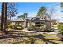 Charming single-story brick home featuring manicured landscaping, a circular driveway, and mature trees at 3148 River Bluff Ln., Little River, SC 29566