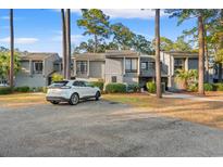 Exterior view of a multi-story townhome with neutral paint, mature trees, and a paved parking area at 328 Salt Marsh Circle # 9D, Pawleys Island, SC 29585