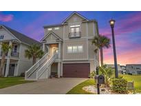 Charming two-story coastal home boasting a garage, stairway, and well-manicured landscaping at twilight at 350 Harbour View Dr., Myrtle Beach, SC 29579