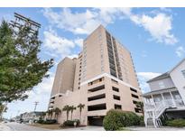 View of condo building with on-site parking and palm tree landscaping on a sunny day at 4103 N Ocean Blvd. # 207, North Myrtle Beach, SC 29582