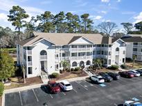 Well-maintained condo building with multiple stories, private balconies, ample parking, and lush landscaping at 4420 Eastport Blvd. # M12, Little River, SC 29566