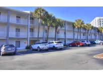 Condo building exterior with white balconies, palm trees, and ample parking at 6803 N Ocean Blvd. # 233, Myrtle Beach, SC 29577