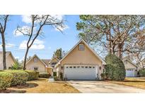 Charming tan home with a two-car garage and mature trees in the front yard at 876 Antiqua Dr., Myrtle Beach, SC 29572