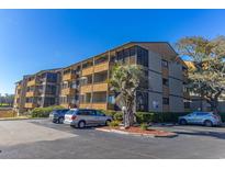 Multi-story condo building featuring screened porches, lush landscaping, and ample parking at 9501 Shore Dr. # A-314, Myrtle Beach, SC 29572