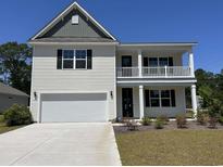 Charming two-story home with a covered porch, two-car garage, and landscaped front yard at 104 Fair Meadow Ct., Loris, SC 29569