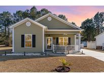 Charming single-story home featuring an inviting front porch with a white picket fence and manicured lawn at 129 Tomoka Trail, Longs, SC 29568