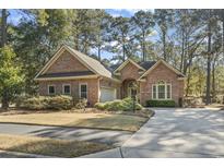 Charming brick home featuring a well-manicured lawn, mature trees, and an attached two-car garage at 17 Montrose Ln., Pawleys Island, SC 29585