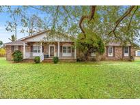 Charming brick home with covered porch and a spacious front yard filled with lush, green leaves at 2560 Wise Rd., Conway, SC 29526