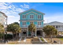 Charming two-story coastal home in blue with white trim and palm trees at 84 Wilmington St., Ocean Isle Beach, NC 28469