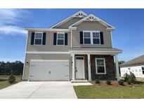Charming two-story home boasts a stone accent wall, attached garage, and well-manicured lawn at 990 Oak Hollow St., Longs, SC 29568