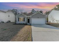 Charming single-story home with gray siding, a two-car garage, and a well-maintained front yard at 135 Harmony Ln., Myrtle Beach, SC 29588