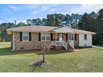 Inviting brick home featuring a cozy front porch and well-maintained front yard at 140 Flag Patch Rd., Loris, SC 29569