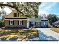 Charming brick home featuring a well-manicured lawn and an inviting, long driveway at 221 Portrush Loop, Pawleys Island, SC 29585