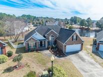 Beautiful brick two-story home with manicured lawn, attached garage and adjacent lake views at 227 Old Hickory Dr., Conway, SC 29526