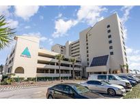 Exterior view of the condo building, a parking garage, and multiple parked cars in front at 6100 Ocean Blvd. N # 804, North Myrtle Beach, SC 29582