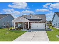 Charming home with a two-car garage, stone accents, and a welcoming front porch seating area at 1309 Willow Run Dr., Little River, SC 29566