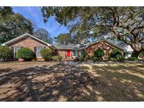 Charming single-story brick home featuring a vibrant red front door and mature landscaping at 304 Queens Rd., Myrtle Beach, SC 29572