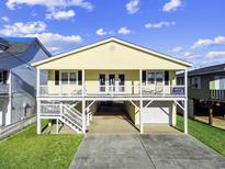 Charming yellow beach home with covered parking, front porch, and coastal charm on a sunny day at 314 58Th Ave. N, North Myrtle Beach, SC 29582