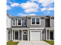 New gray townhome featuring an attached white garage, covered porch, and well-maintained landscaping at 319 Sandridgebury Dr. # 71, Little River, SC 29566