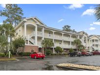 Inviting yellow condo building featuring a charming architectural style and ample parking at 4161 Hibiscus Dr. # 15-302, Little River, SC 29566