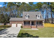 Charming brick home featuring dormer windows, a manicured lawn, and an attached two-car garage at 4350 Goude St., Murrells Inlet, SC 29576