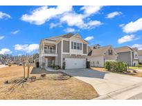 Charming two-story home with a covered balcony, stone accents, manicured landscaping, and a two-car garage at 5572 Redleaf Rose Dr., Myrtle Beach, SC 29579