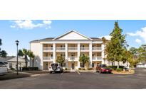 Three-story condo building featuring white pillars, multiple balconies, and well-maintained landscaping at 611 Woodmoor Dr. # 301, Murrells Inlet, SC 29576