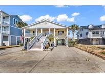 Inviting raised beach house with a charming yellow exterior, white columns, and ample parking at 638 S Waccamaw Dr., Murrells Inlet, SC 29576