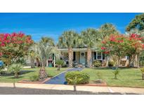 Charming single-story home boasts a lush lawn with palm trees, vibrant flowerbeds, and a welcoming walkway at 7609 Driftwood Dr., Myrtle Beach, SC 29572