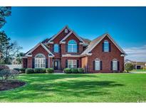 Beautiful brick two-story home with manicured lawn and lush landscaping creating stunning curb appeal at 1585 Brookgreen Dr., Myrtle Beach, SC 29577