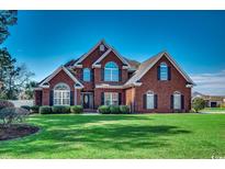 Charming two-story brick home with manicured lawn, lush shrubbery, and classic architectural details at 1585 Brookgreen Dr., Myrtle Beach, SC 29577